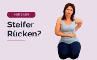 Nicole sitzt im Fersensitz und fasst sich mit einer Hand an den unteren Rücken