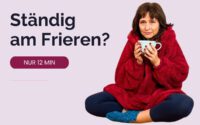 Nicole sitzt im Schneidersitz in einem dicken roten Pullover und hält eine Tasse mit beiden Händen